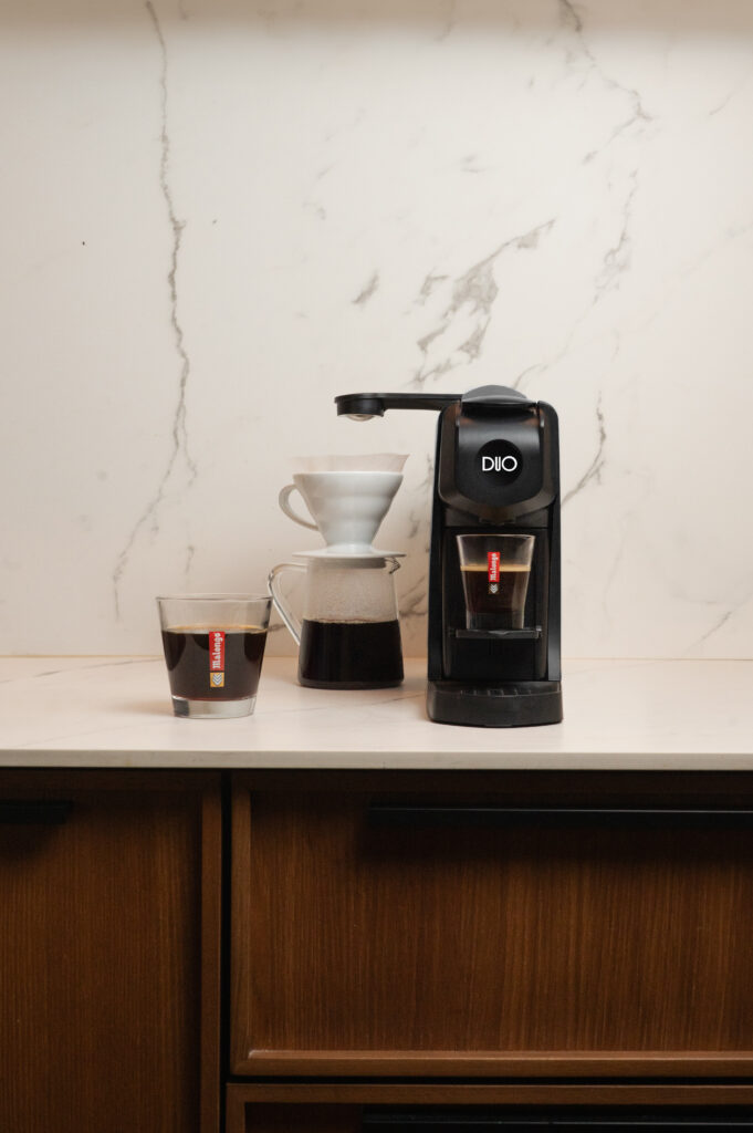 Machine à café combinée DUO, posé sur une table à cote d'un expresso